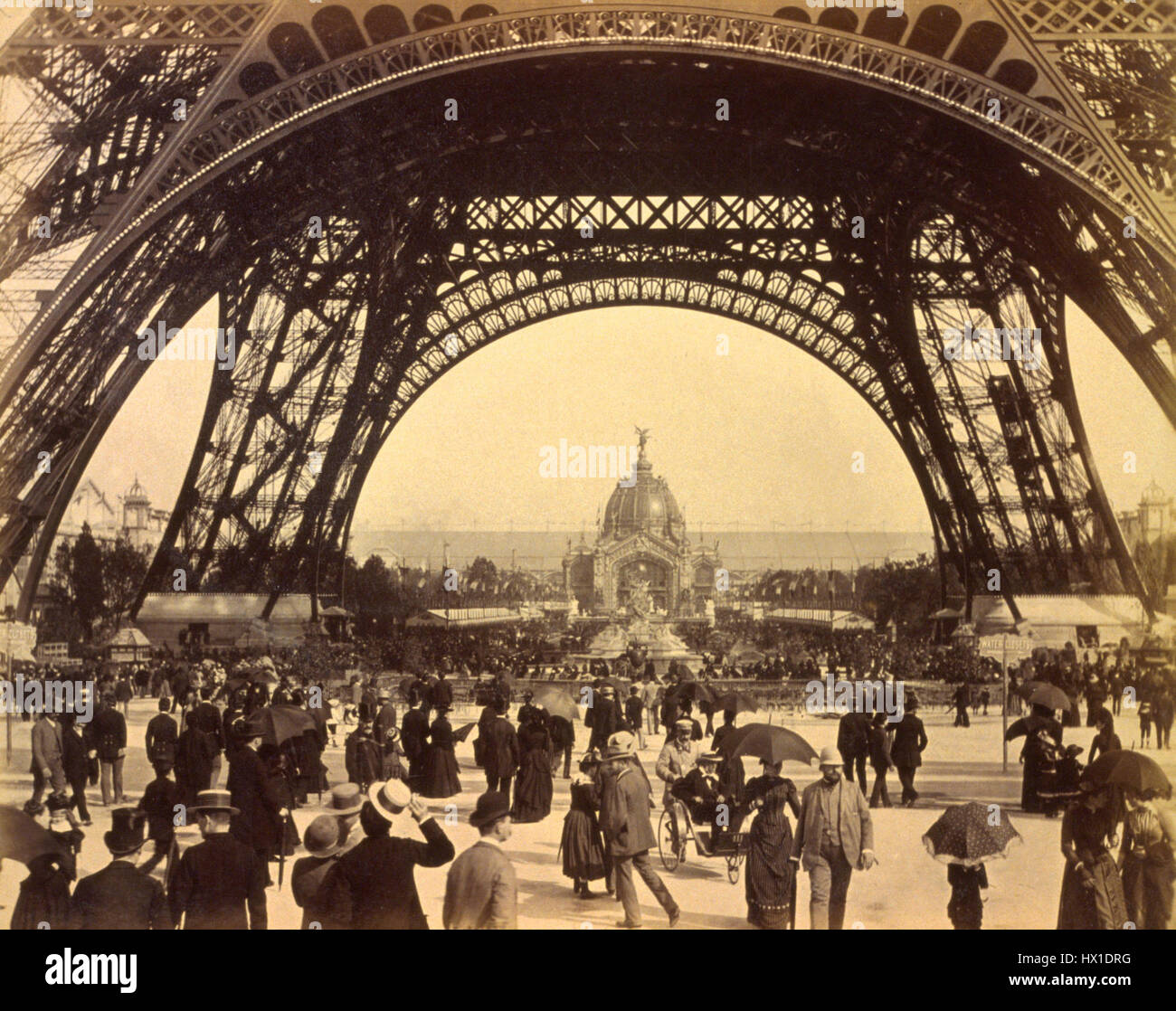 Une photographie capturant une foule de personnes sous la Tour Eiffel lors de l'exposition de Paris de 1889. La scène met en évidence l'échelle de la tour et l'excitation entourant l'événement. Banque D'Images Une photographie capturant une foule de personnes sous la Tour Eiffel lors de l'exposition de Paris de 1889. La scène met en évidence l'échelle de la tour et l'excitation entourant l'événement. Banque D'Images