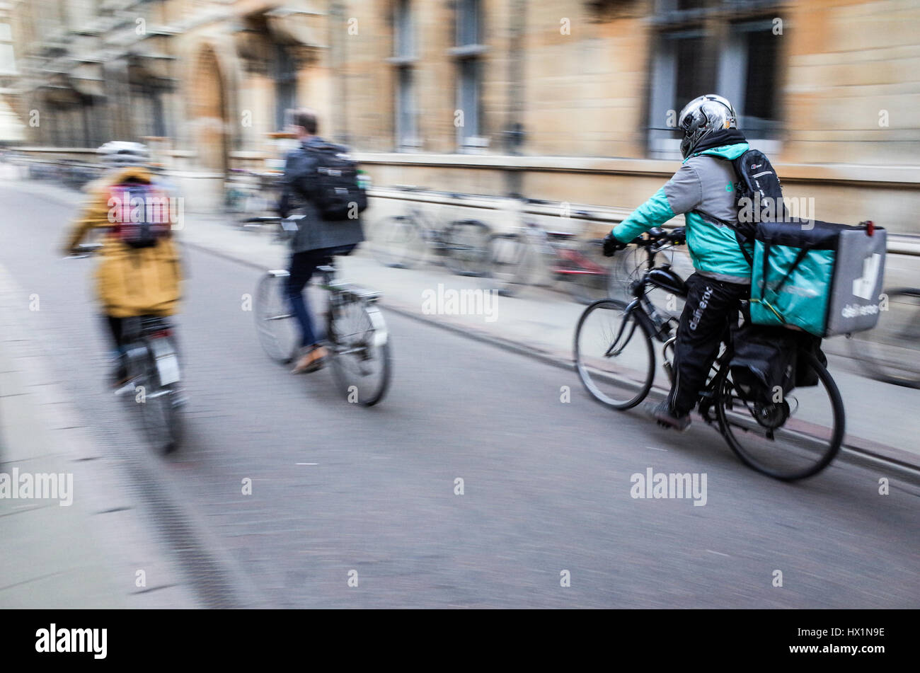 Un Deliveroo courier alimentaire s'engouffre dans les rues de Cambridge, UK, pour livrer de la nourriture à emporter aux clients qui commandent sur leur smartphone. Banque D'Images