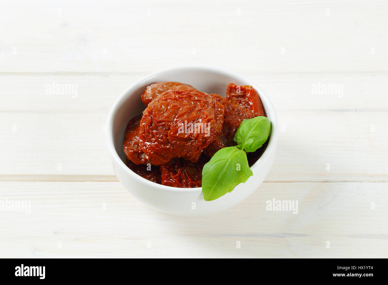 Bol de tomates marinées et séchées sur fond blanc Banque D'Images