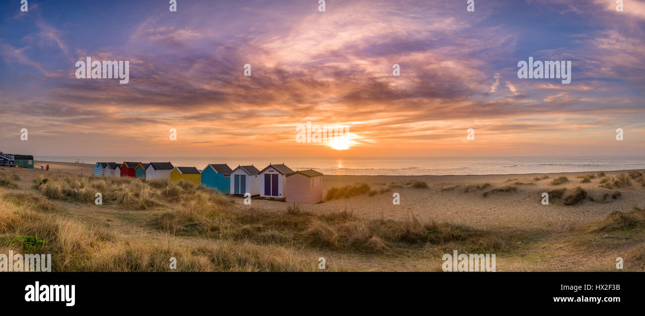 Sur une aube calme à la mi-mars, le soleil se lève sur la célèbre ligne de cabines de plage sur les dunes de la ville balnéaire de Suffolk Southwold. Banque D'Images