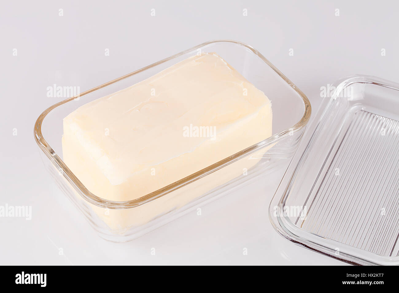 Le beurre dans un récipient en verre isolé sur un fond blanc. Banque D'Images