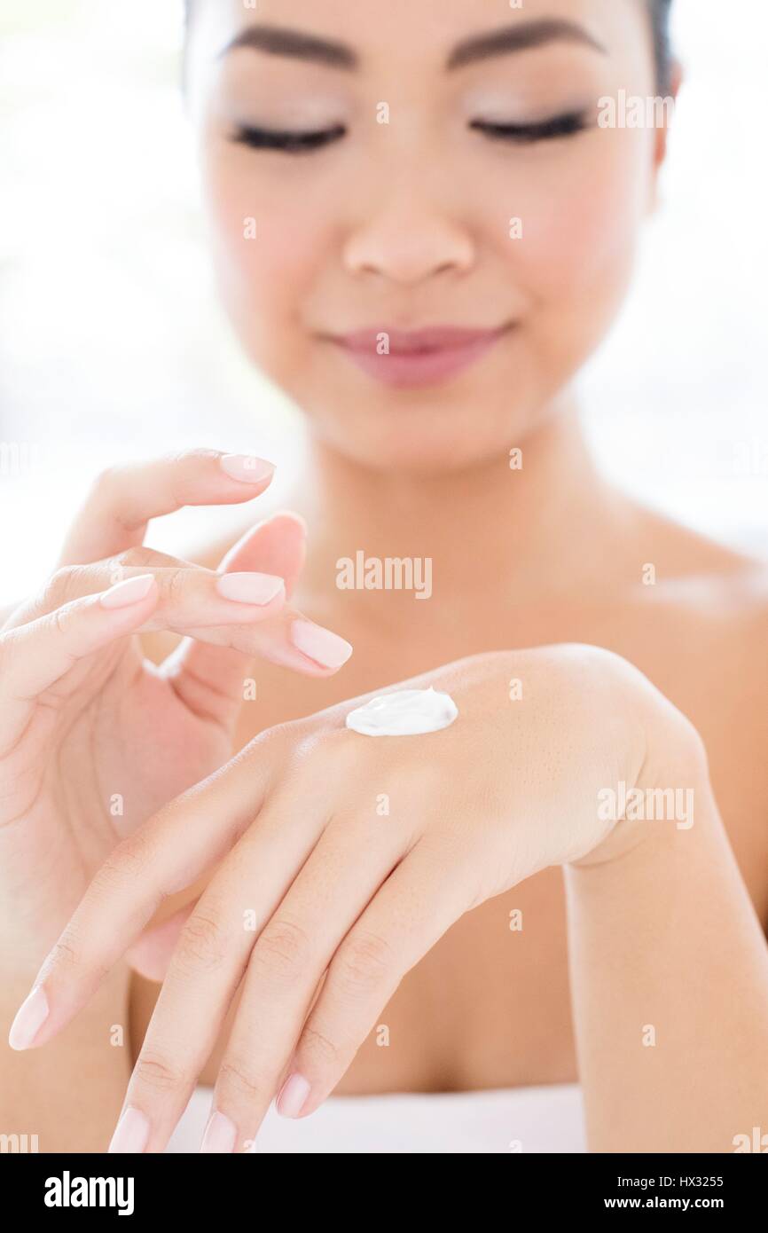 Parution du modèle. Young Asian woman applying cream à part, portrait. Banque D'Images