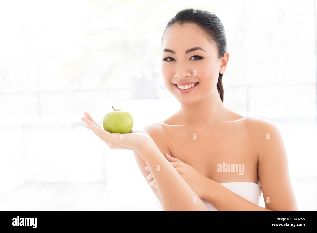 Parution du modèle. Young Asian woman holding apple, portrait. Banque D'Images