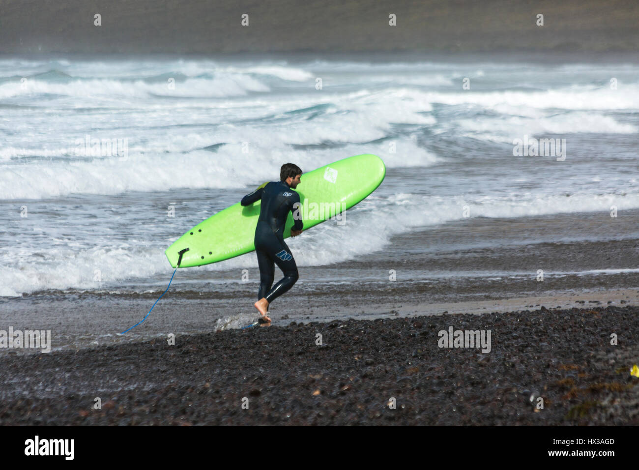 Homme avec green surf sur la plage de Famara Lanzarote Banque D'Images