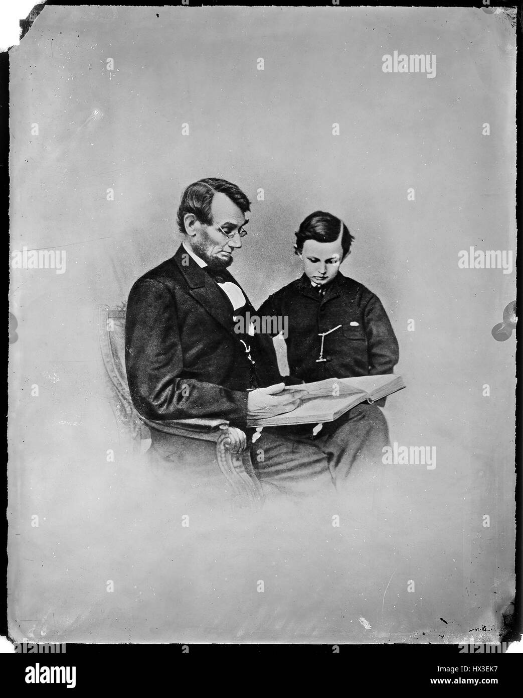 Portrait de l'ex-président des États-Unis Abraham Lincoln assis et lire un livre à son plus jeune fils, Tad Lincoln, 1863. L'image de courtoisie des Archives nationales. Banque D'Images