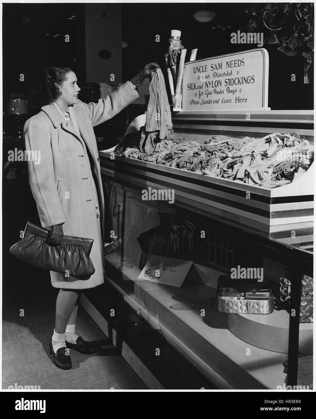 Cadre d'une campagne de collecte des bas nylon pour les efforts américains pendant la Seconde Guerre mondiale, une jeune femme soutient une paire de collants qui dissous seront recyclés en sacs de poudre à canon, 1942. L'image de courtoisie des Archives nationales. Banque D'Images