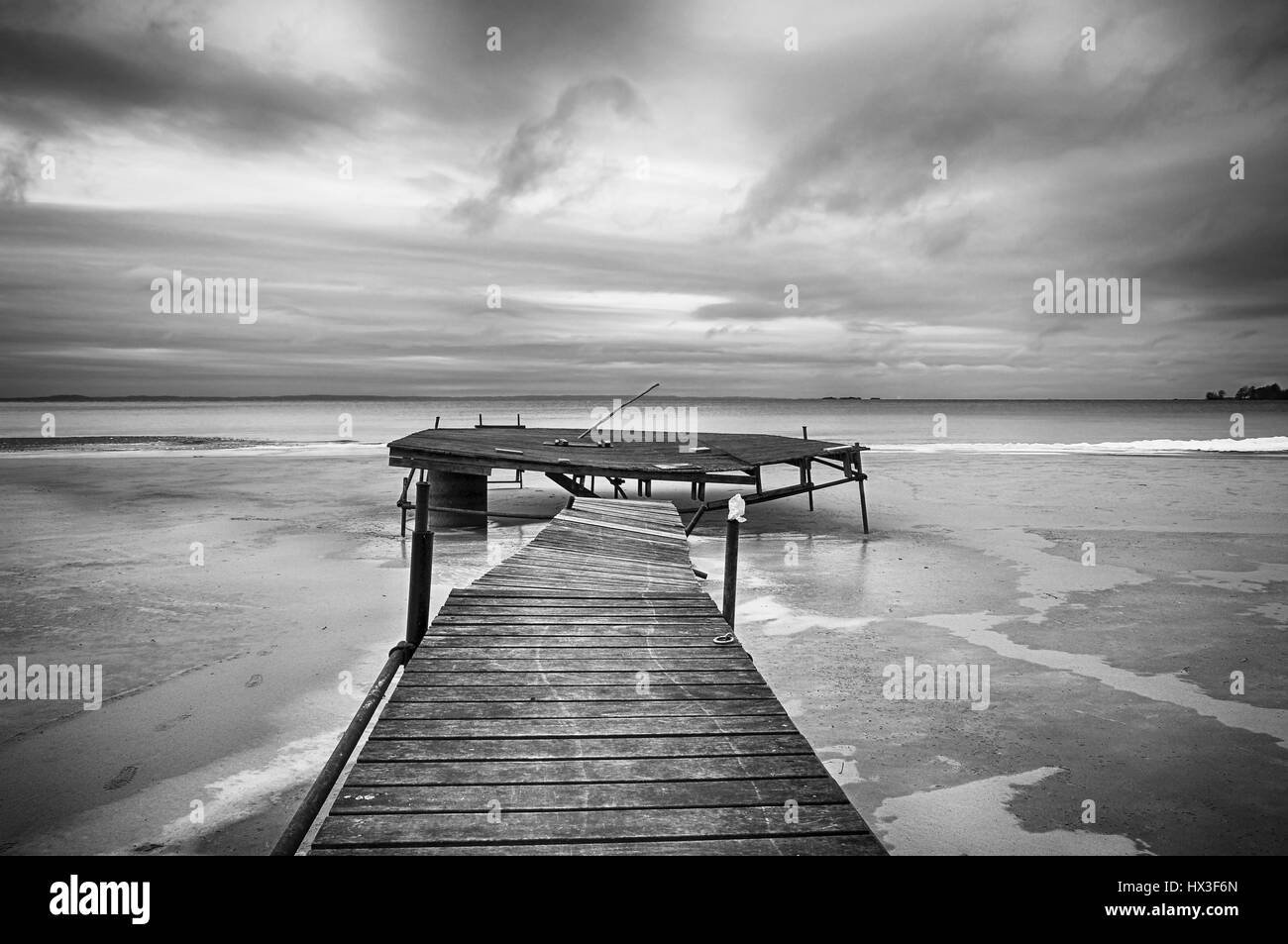 Image en noir et blanc de jetée sur une plage en hiver. Banque D'Images