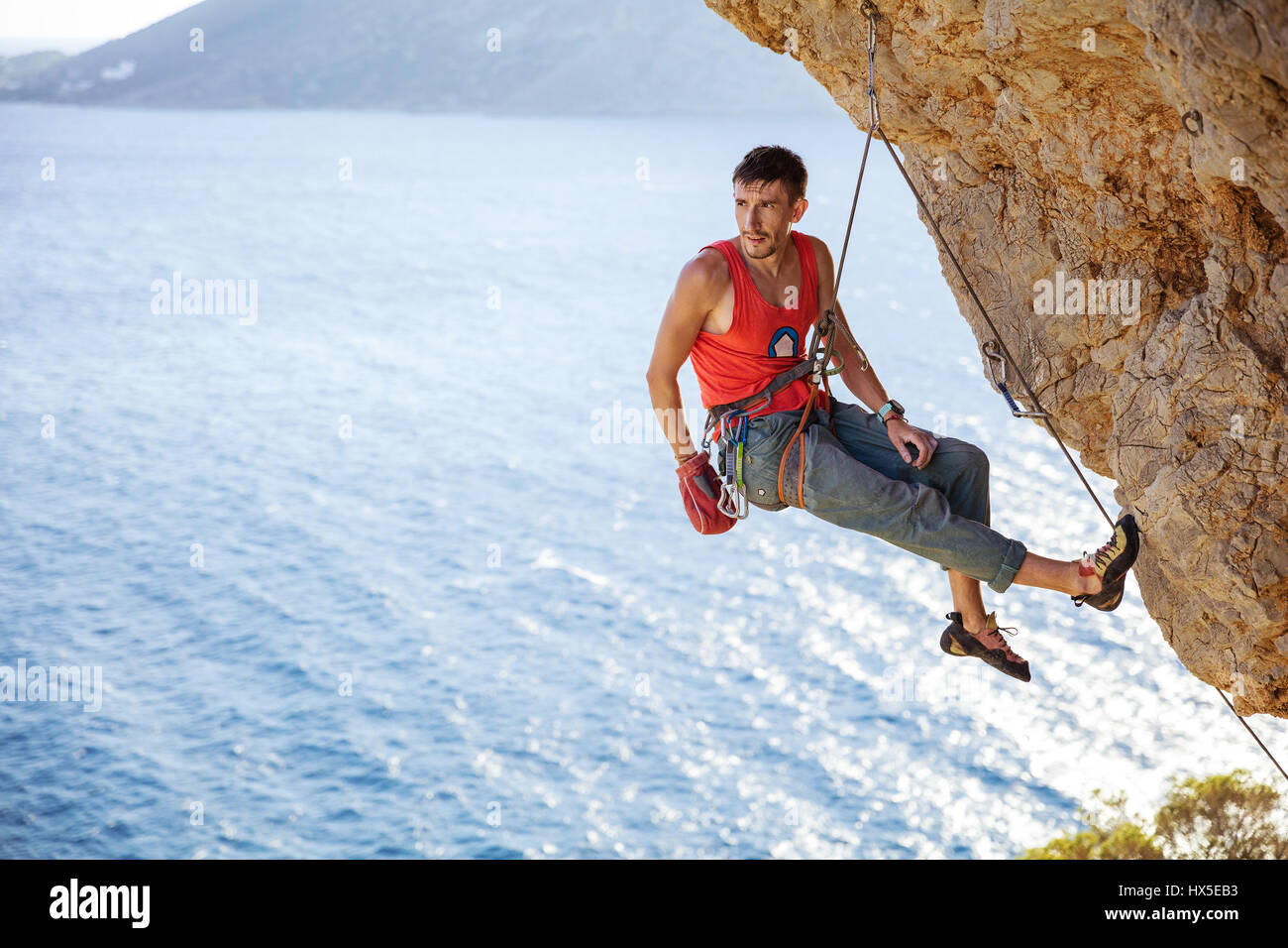 Male rock climber resting while hanging sur corde avant la prochaine tentative sur route difficile Banque D'Images