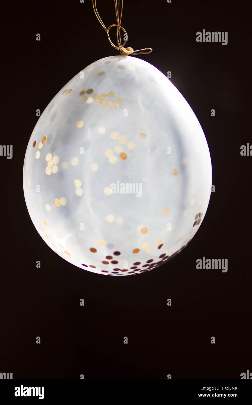 Un seul ballon confettis semble glow sur un fond sombre à l'éclairage naturel Banque D'Images