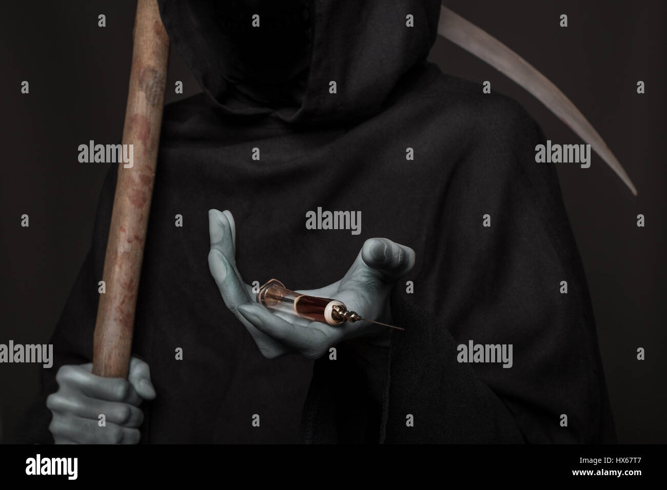 Le concept : les drogues tuent. Grim Reaper holding syringe avec des drogues. Studio shot sur fond noir Banque D'Images