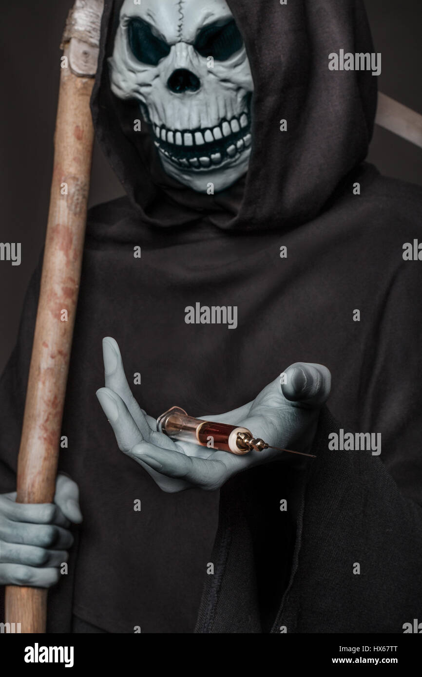Le concept : les drogues tuent. Grim Reaper holding syringe avec des drogues. Studio shot sur fond noir Banque D'Images