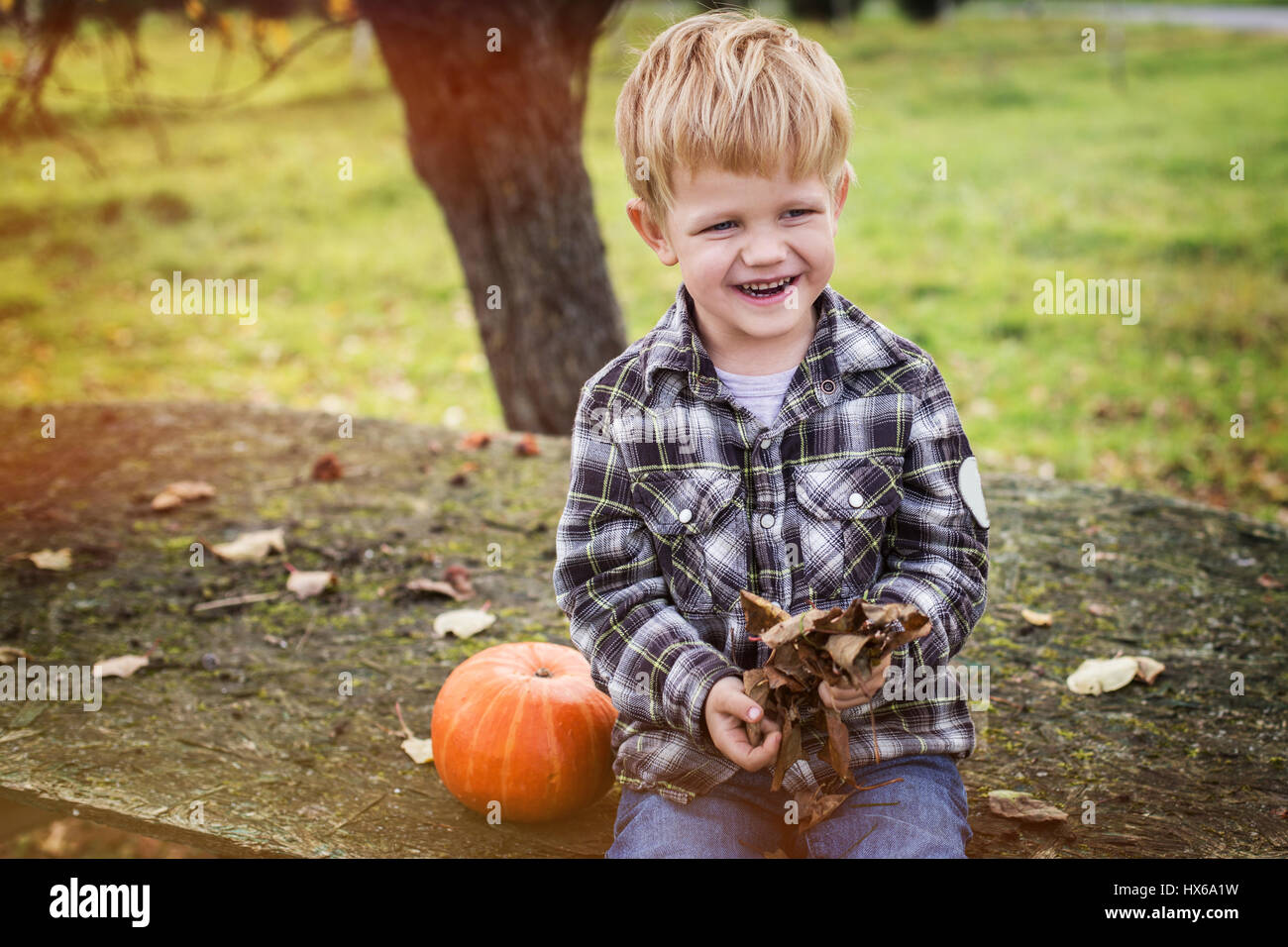 Belle blonde occasionnels enfant assis sur la table en plein air et de rire. De l'automne. Portrait en extérieur Banque D'Images