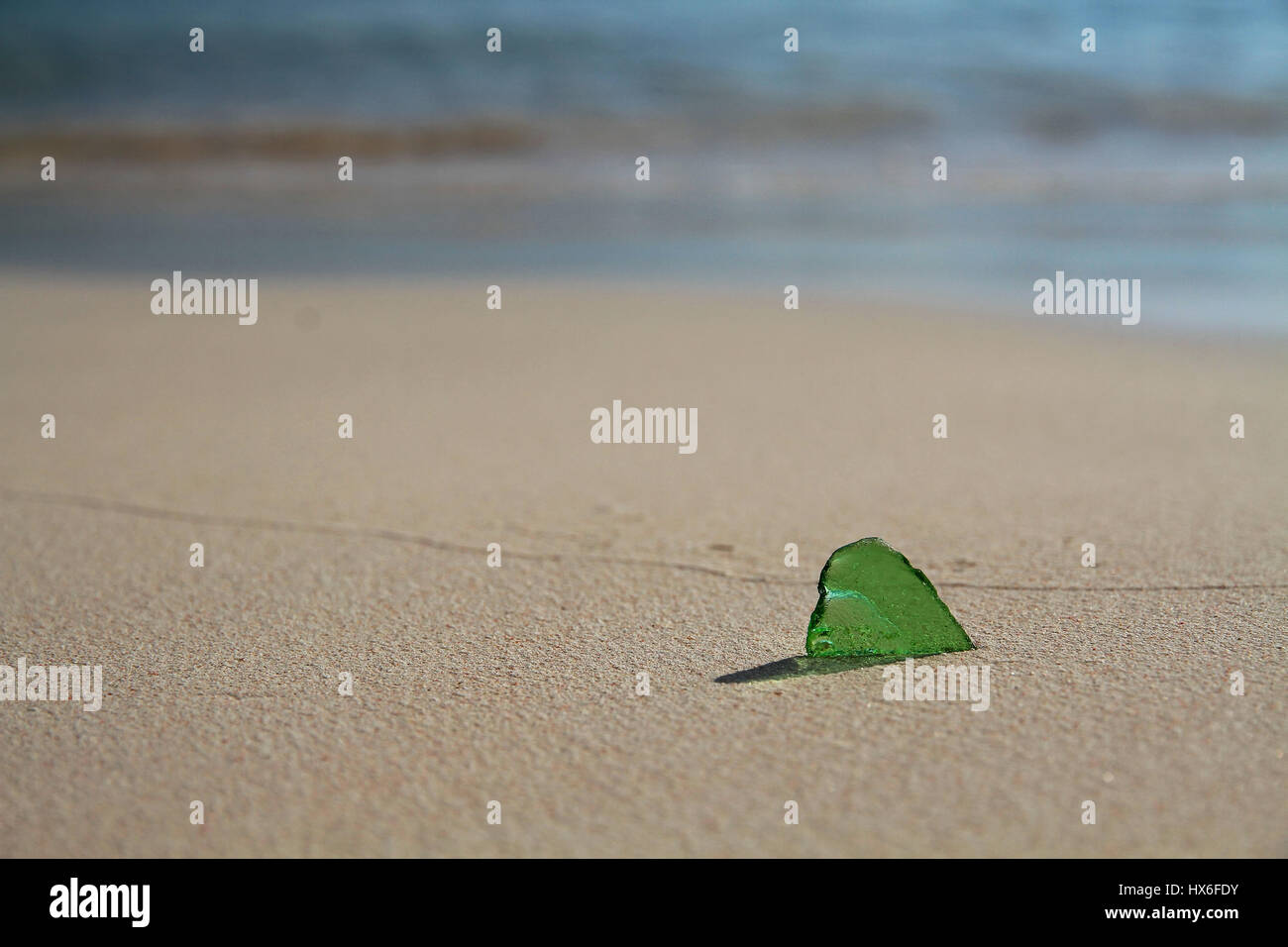 Une seule pièce de verre vert de mer, sur la côte. Le verre est en forme de coeur, et jette une légère ombre sur le sable Banque D'Images