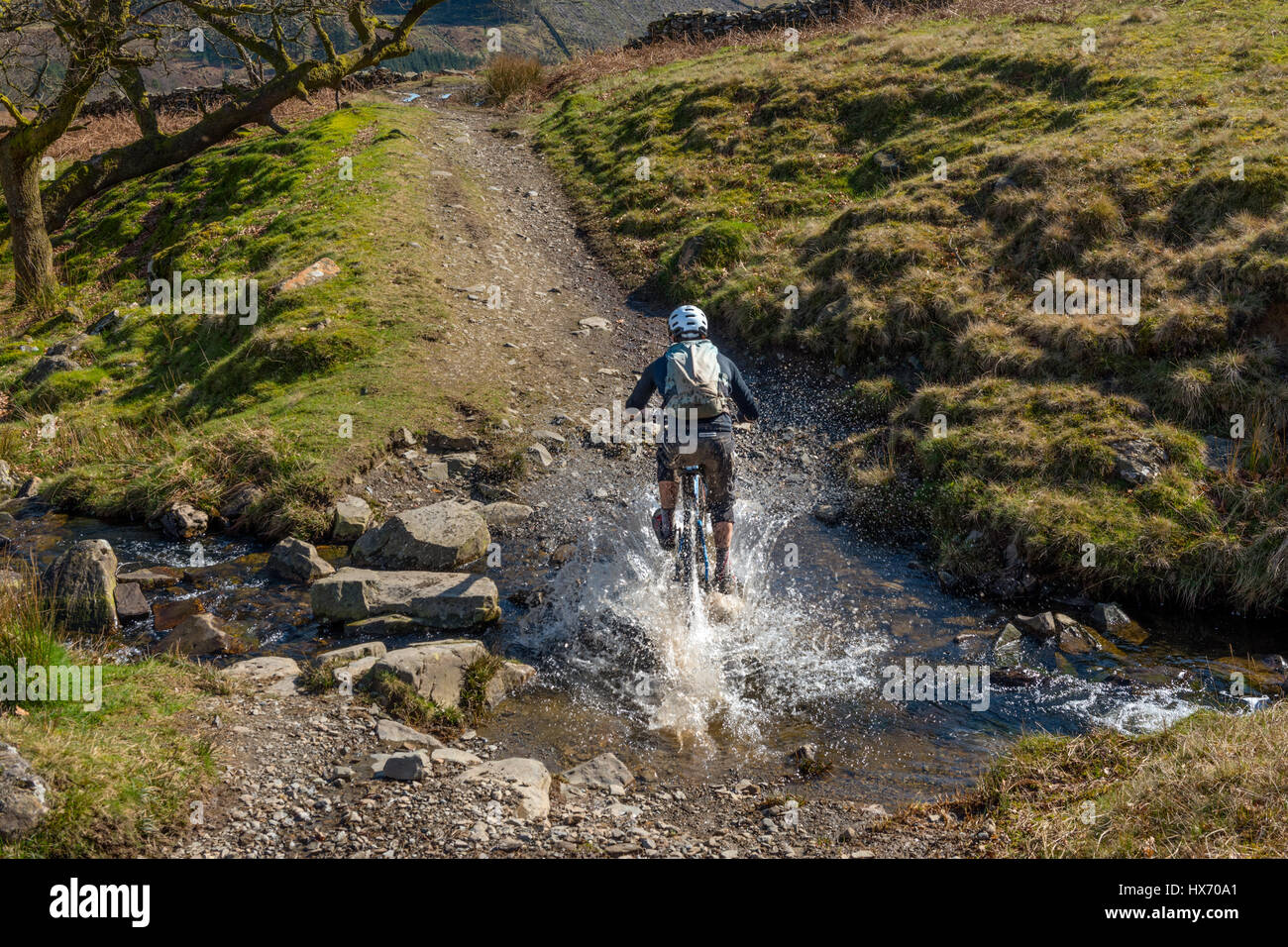 Mountain Biker noir passage Beck dans Cumbria Kentmere Banque D'Images