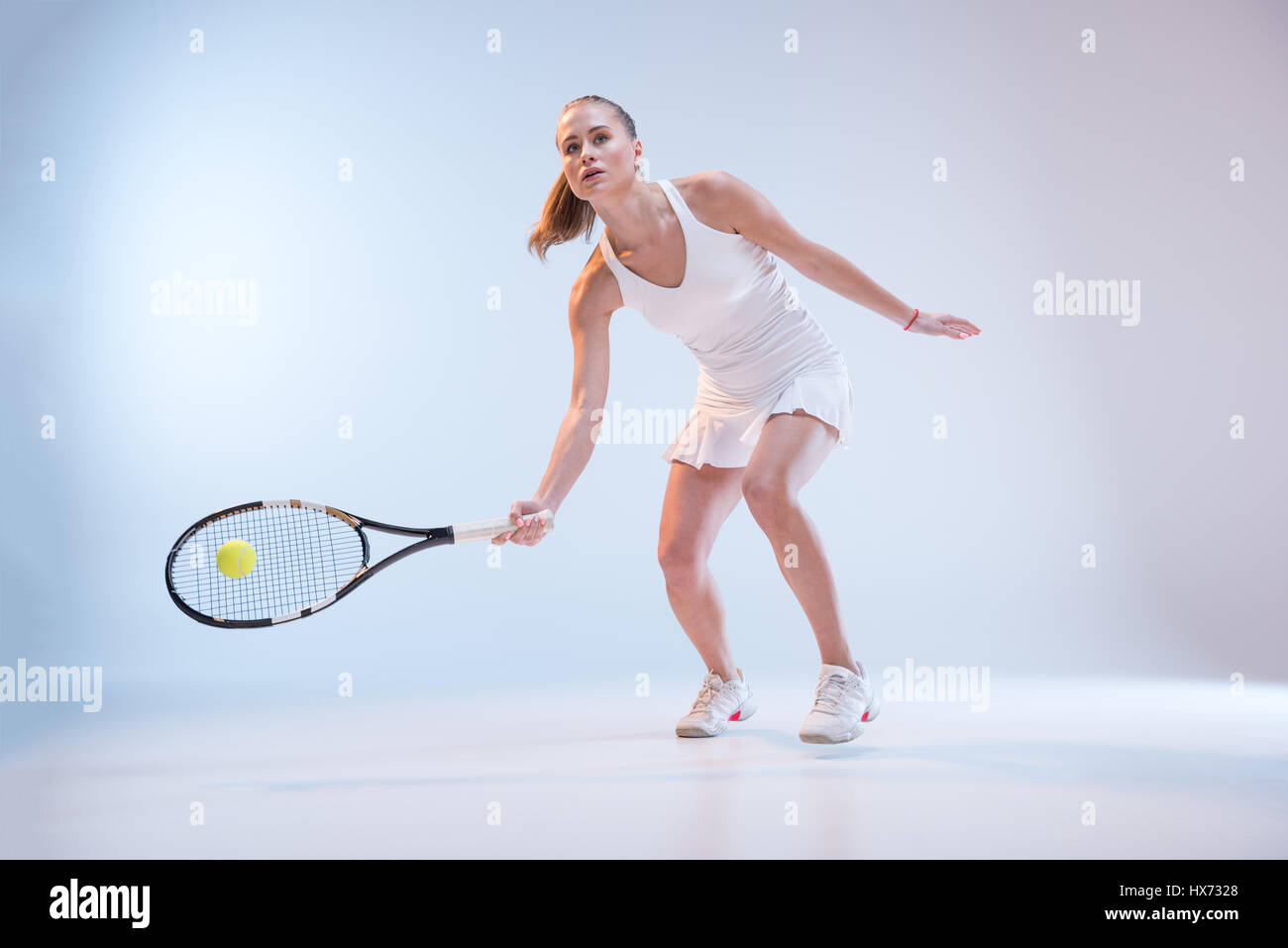 Les jeunes actifs dans les vêtements de sport tennis player hitting ball avec racquet Banque D'Images