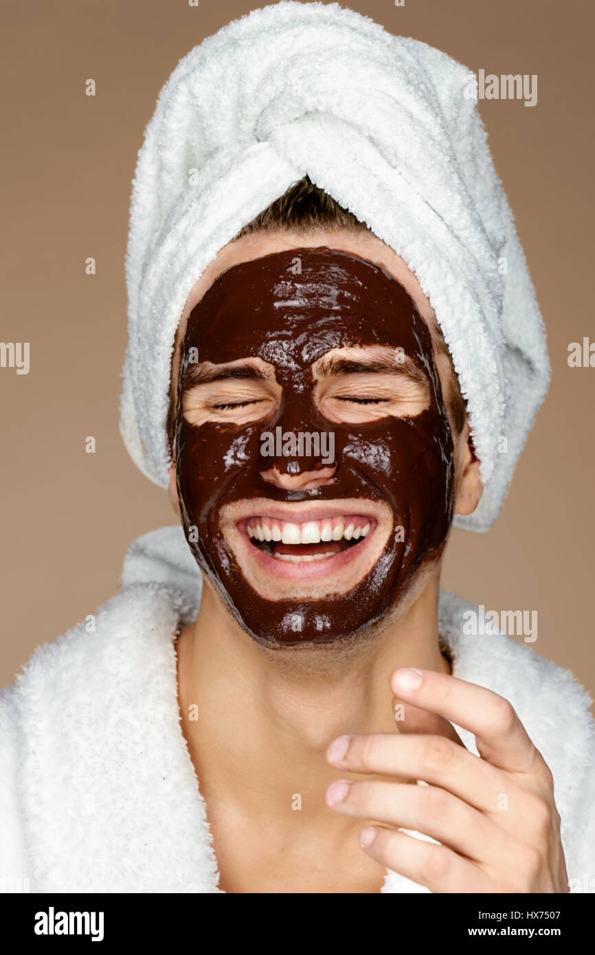 Laughing Man avec masque du visage au chocolat. Photo de grand homme recevant des soins spa. Beauté et Soins De La Peau concept Banque D'Images