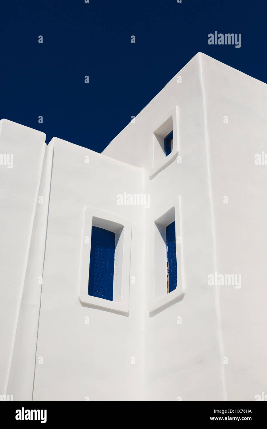 Grec blanchis à la maison aux volets bleus contre un ciel bleu dans un angle angle vue de dessous Banque D'Images