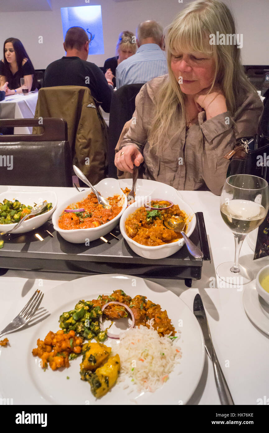 Une femme bénéficiant à des plats au curry Masala épices restaurant indien, Chipping Ongar, Essex, Angleterre Banque D'Images