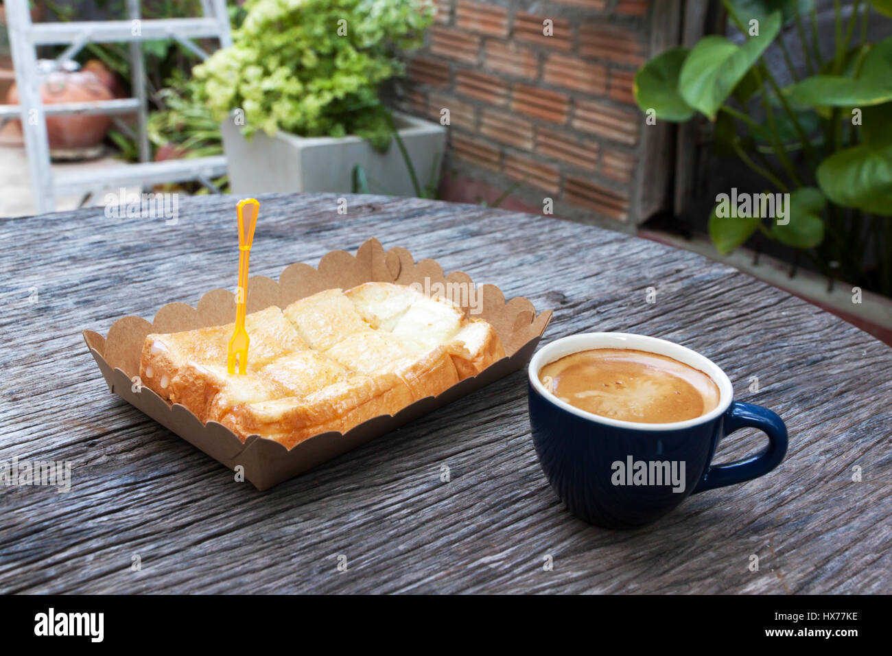 Toast avec du beurre de lait dans le bac papier et sur table bois expresso Banque D'Images