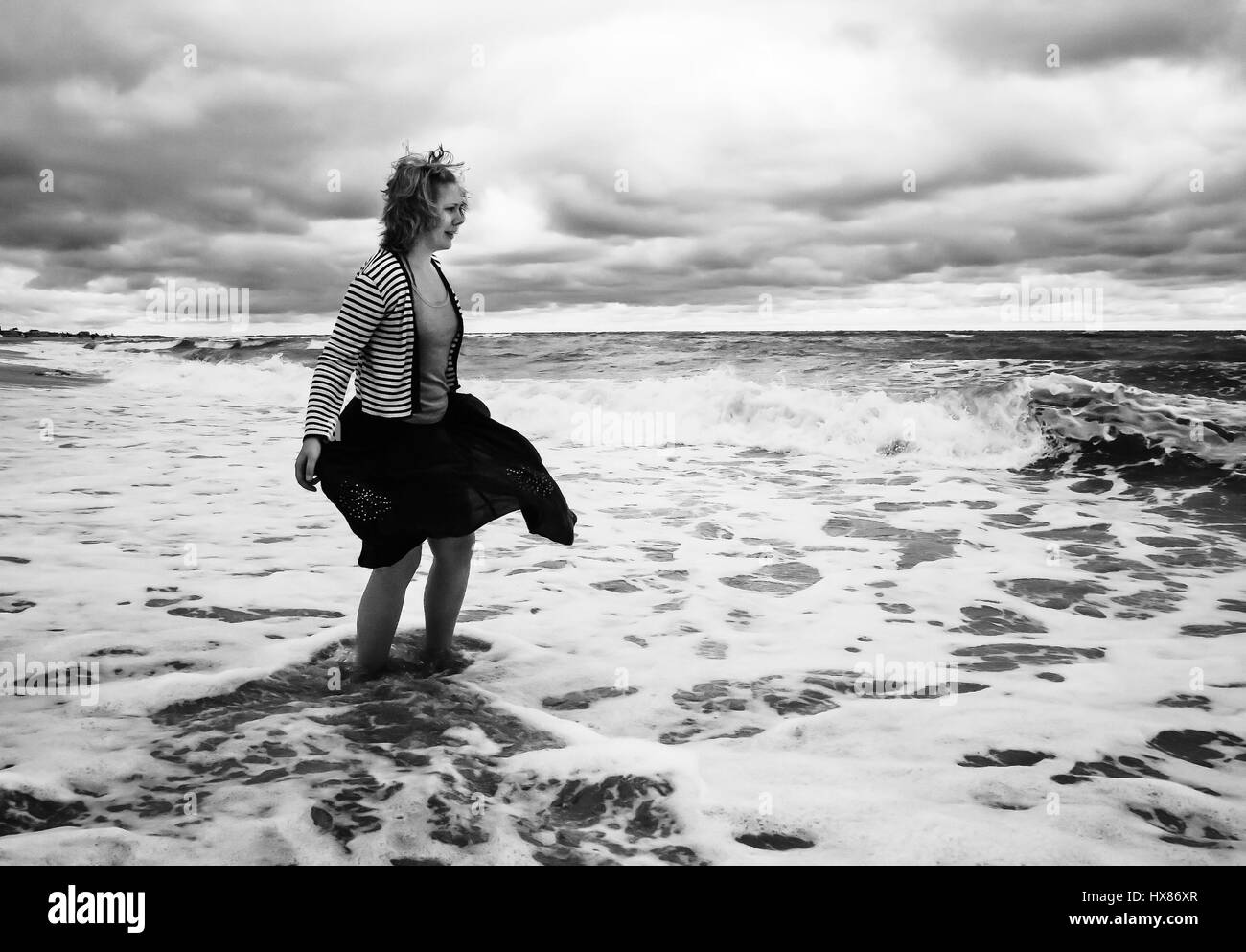Une jeune femme en jupe gonflée est parmi la mer agitée avec des vagues, en  noir et blanc Photo Stock - Alamy