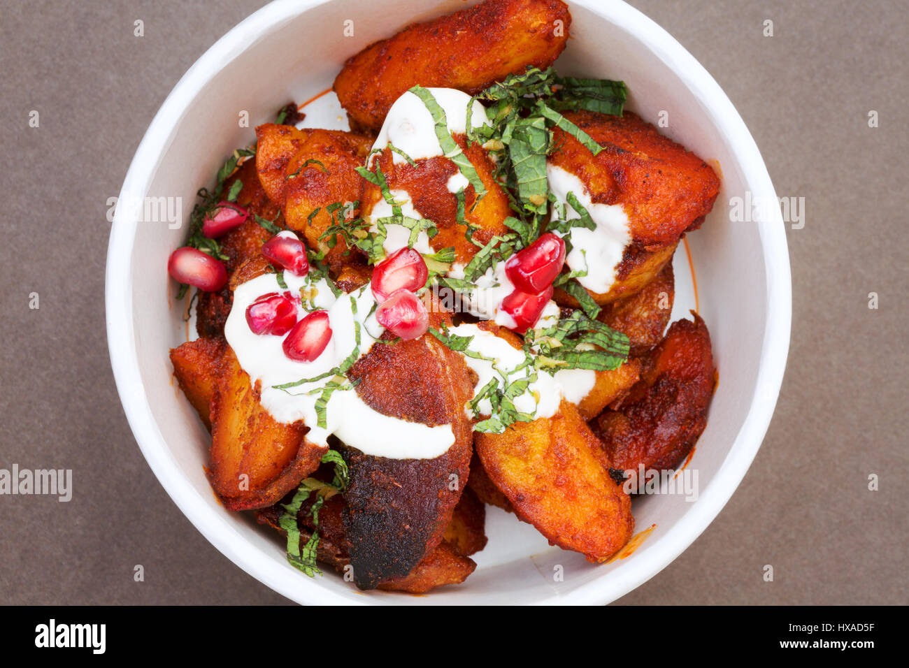 La nourriture végétarienne - saute les pommes de terre avec le paprika fumé et graines de grenade, UK Banque D'Images