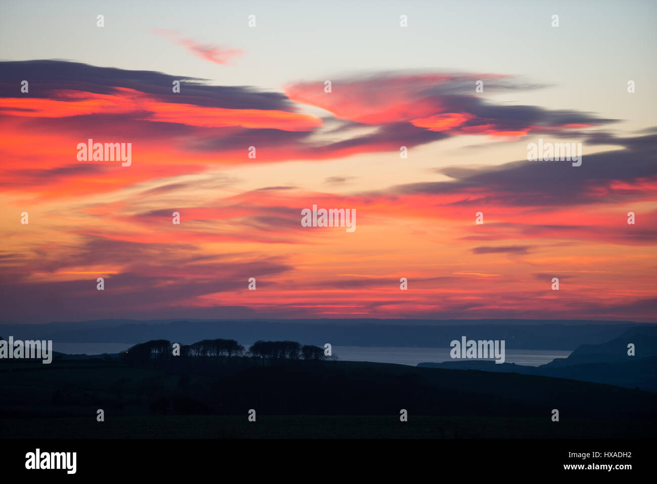 Un rouge ardent coucher de soleil sur la baie de l'ouest vers l'ouest du Dorset et de Lyme Regis après une chaude journée ensoleillée et claire, de monument à Hardy, Dorset, UK. Banque D'Images