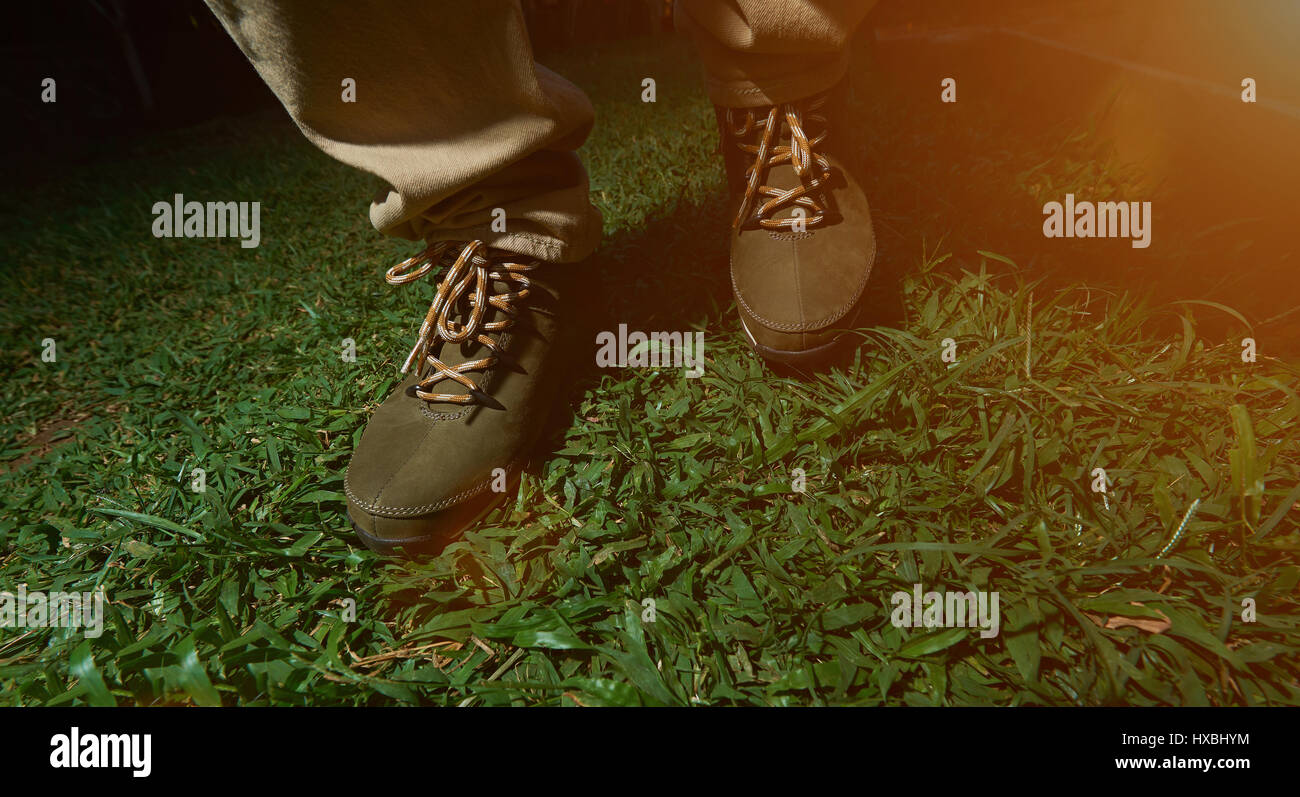 Marcher sur l'herbe verte dans la région de brown chaussures de randonnée. Bottes marron à l'extérieur de gros plan Banque D'Images