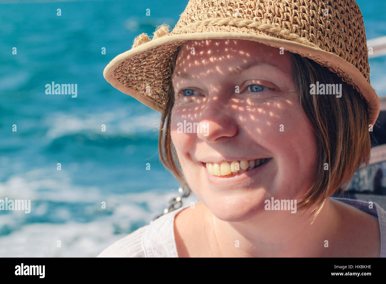 Smiling woman with hat à seaside, heureux et détendu à la femme en distance Banque D'Images