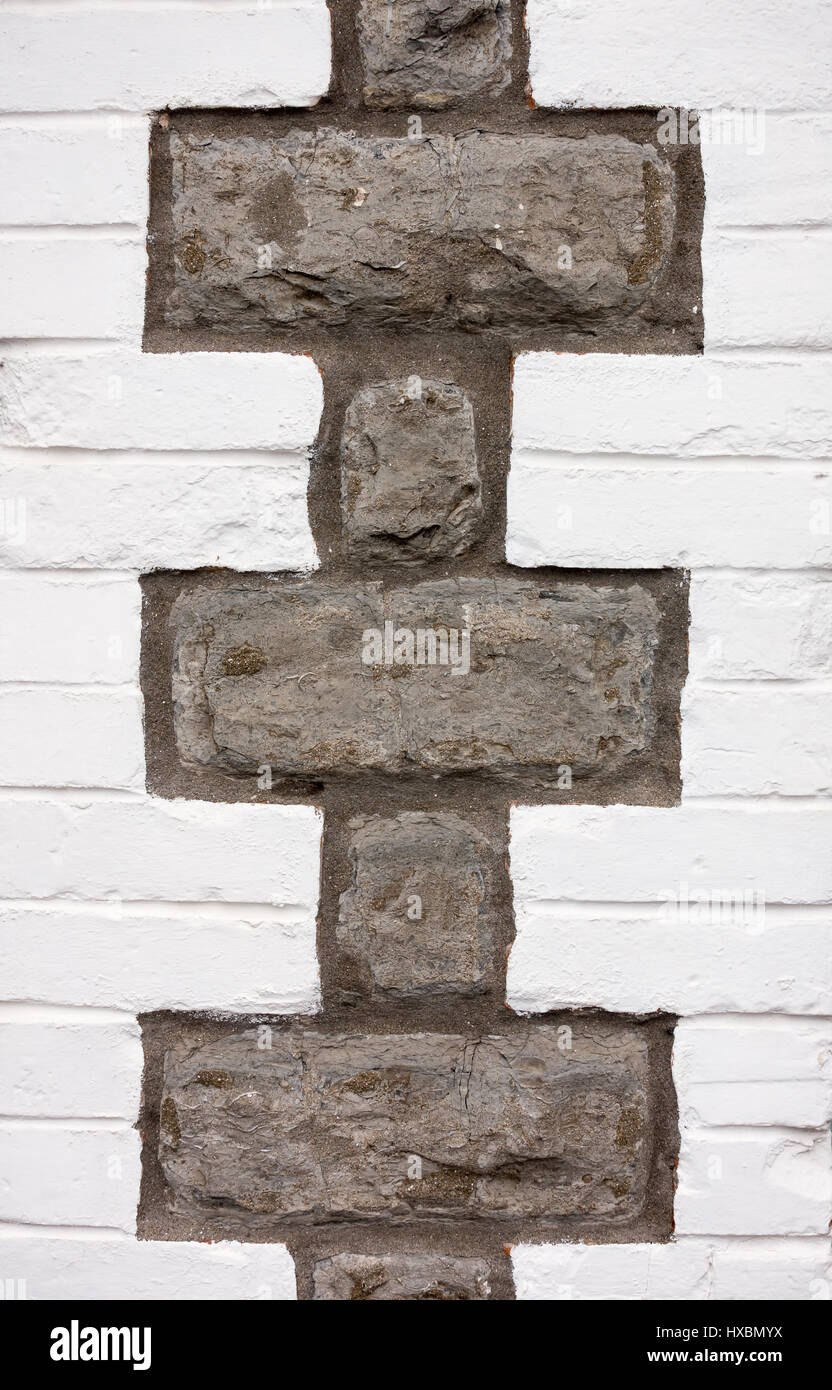 Libre d'un mur de brique peint en blanc avec de grandes pierres gris formant motif intéressant. Banque D'Images