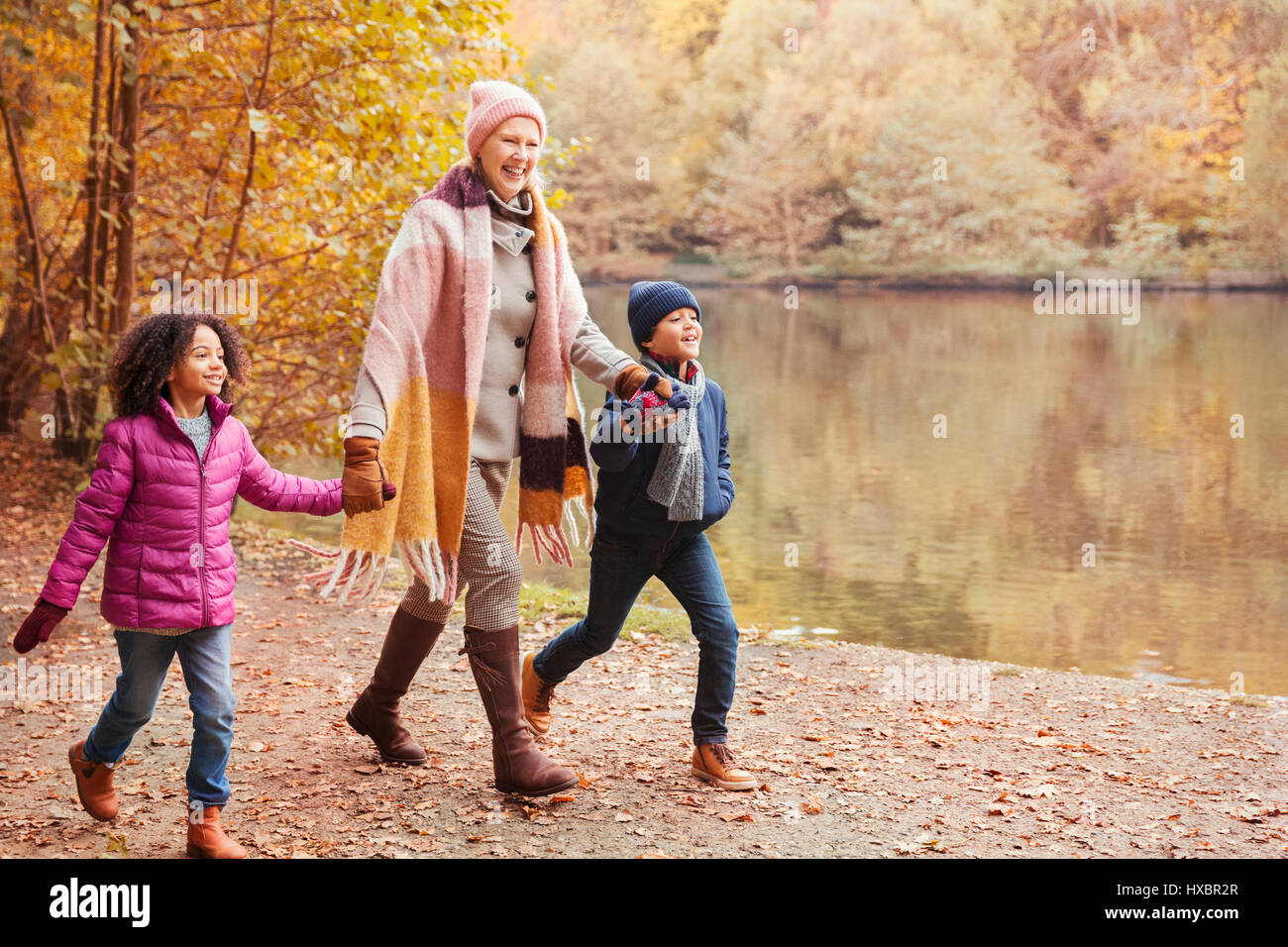 Grand-mère se tenant la main avec petits-enfants marchant le long pond in autumn park Banque D'Images