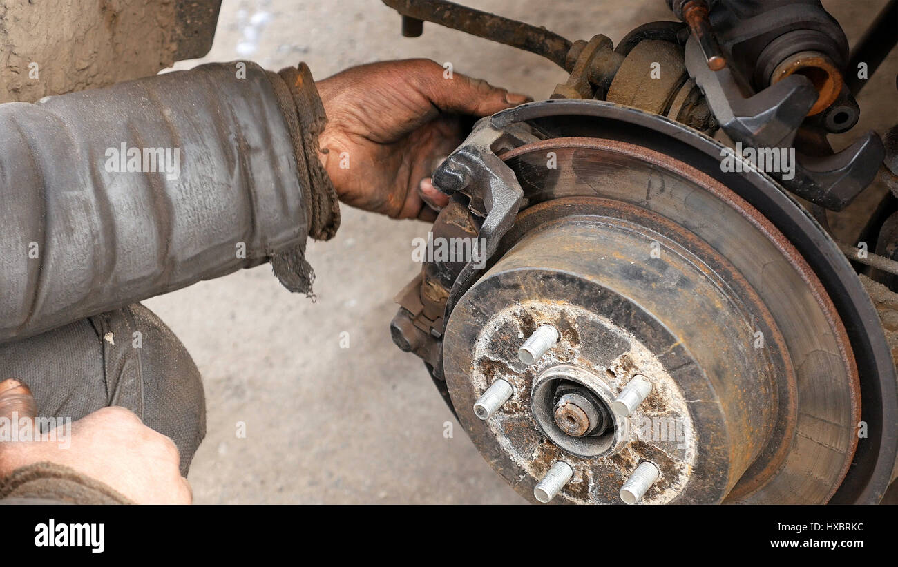 Mécanicien automobile travaillant sur les freins en atelier de réparation de voiture Banque D'Images