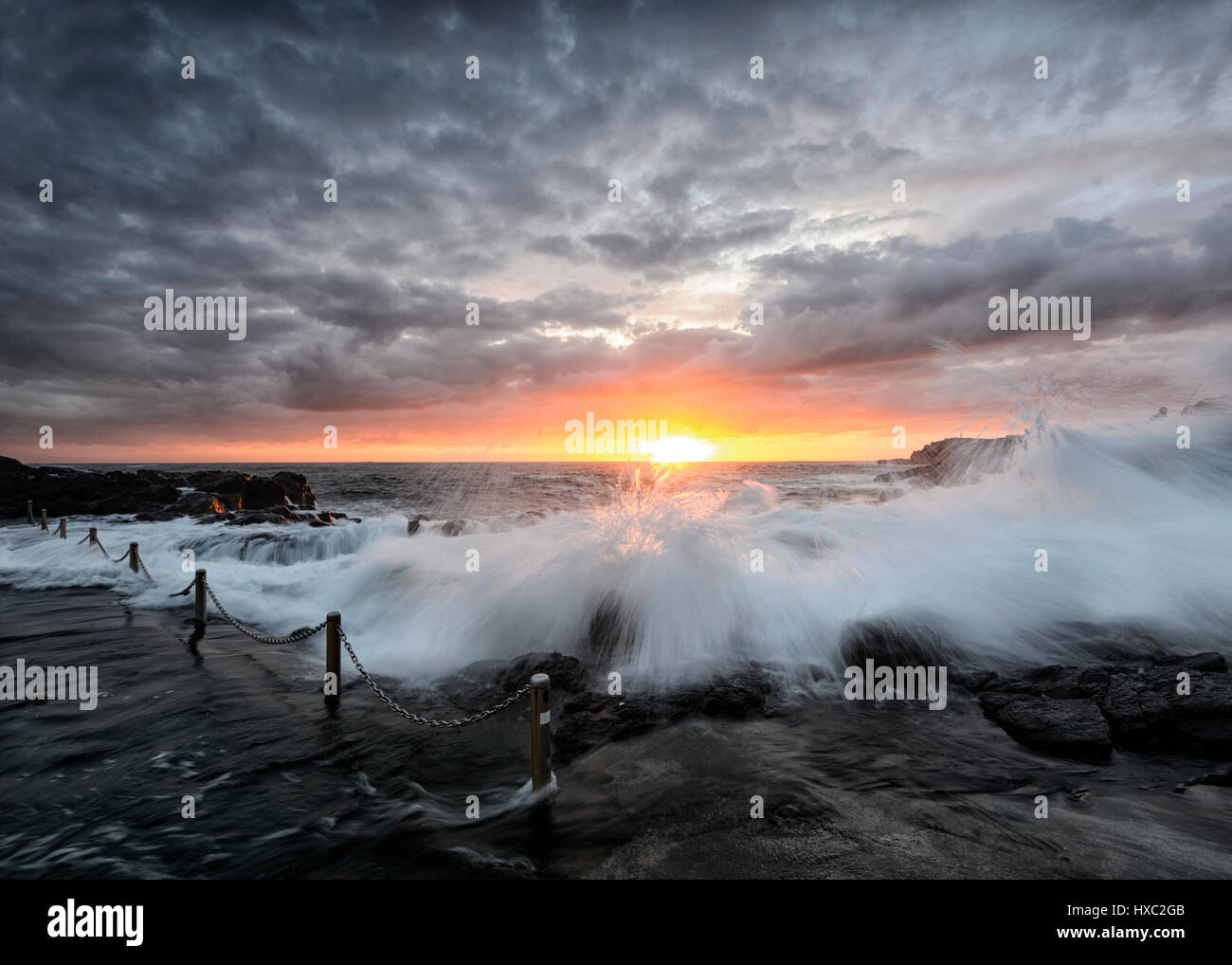 Lever du soleil sur une mer forte avec de grosses vagues, de flou et d'un ciel rose, Kiama Rock Pool, Côte d'Illawarra, New South Wales, NSW, Australie Banque D'Images