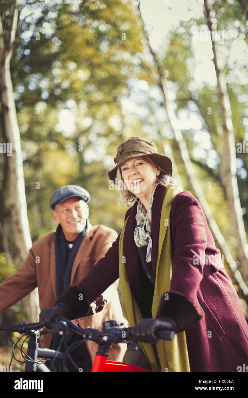 Portrait of smiling senior woman riding bike in autumn park Banque D'Images
