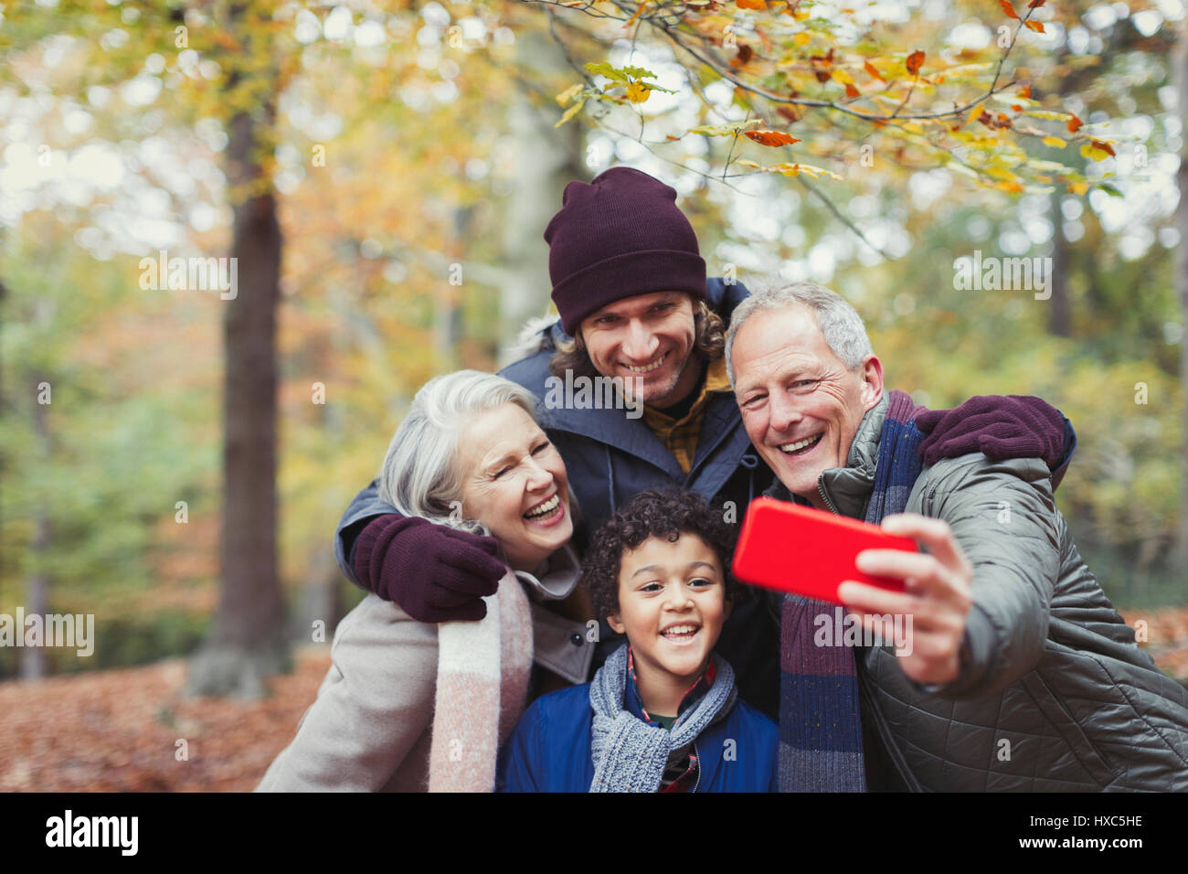 Multi-generation family en tenant avec selfies téléphone appareil photo en automne woods Banque D'Images