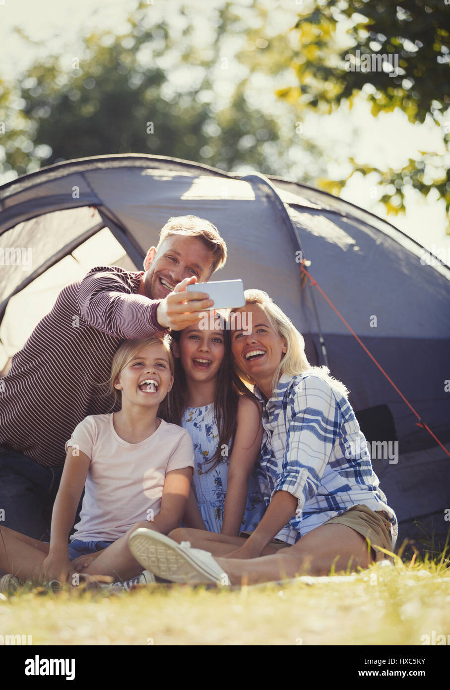 Famille heureuse de prendre l'appareil photo avec téléphone en dehors de selfies sunny camping tente Banque D'Images