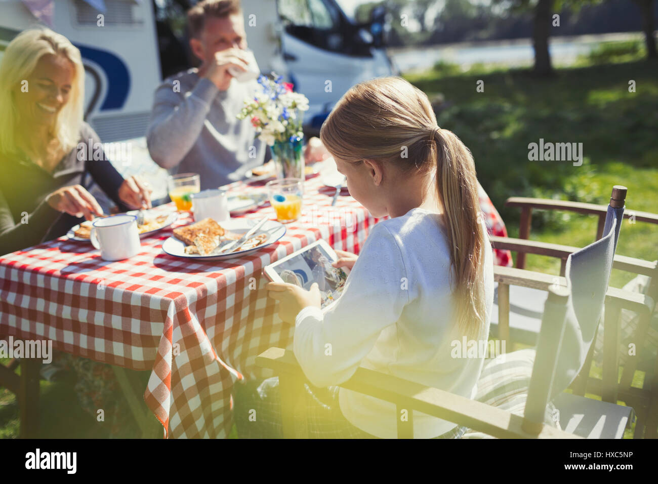 Girl using digital tablet at breakfast table dehors sunny motor home Banque D'Images