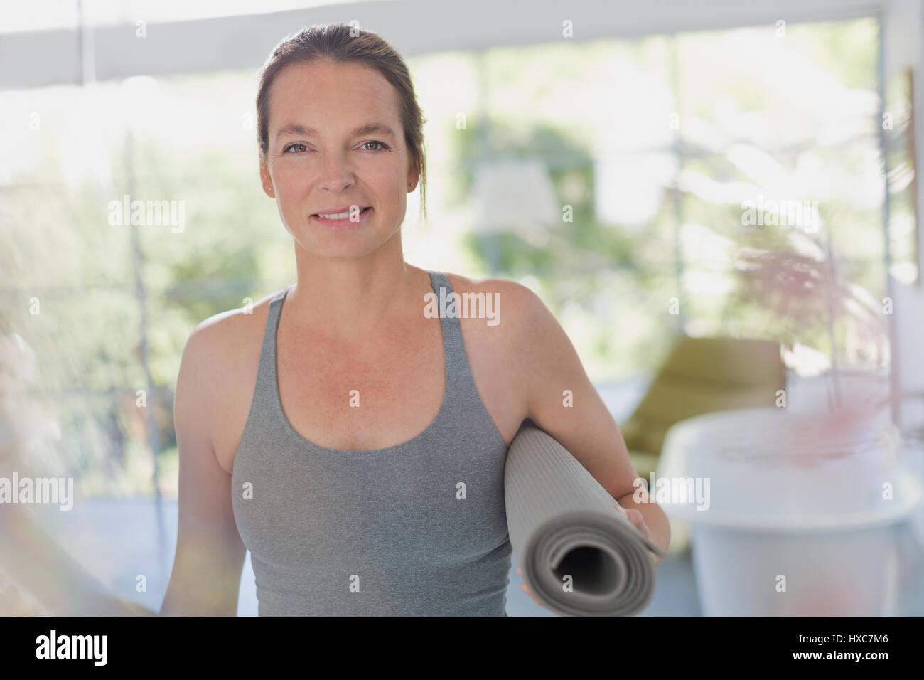 Portrait of smiling mature woman holding yoga mat Banque D'Images