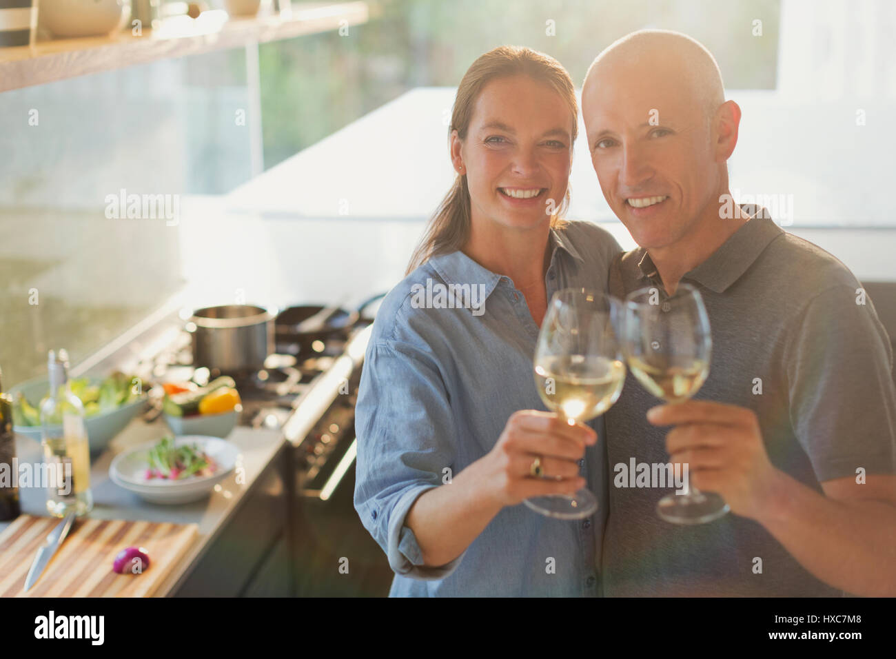 Portrait of mature couple toasting verres à vin blanc, la cuisson dans la cuisine Banque D'Images