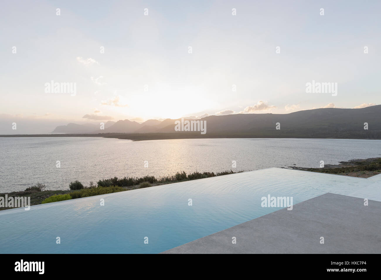 Coucher du soleil au-delà tranquille piscine à débordement et l'océan Banque D'Images
