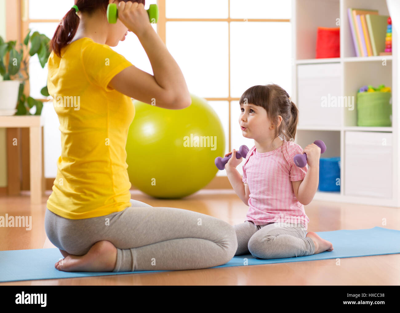 Femme et son enfant fille faisant des exercices de fitness avec haltères Banque D'Images