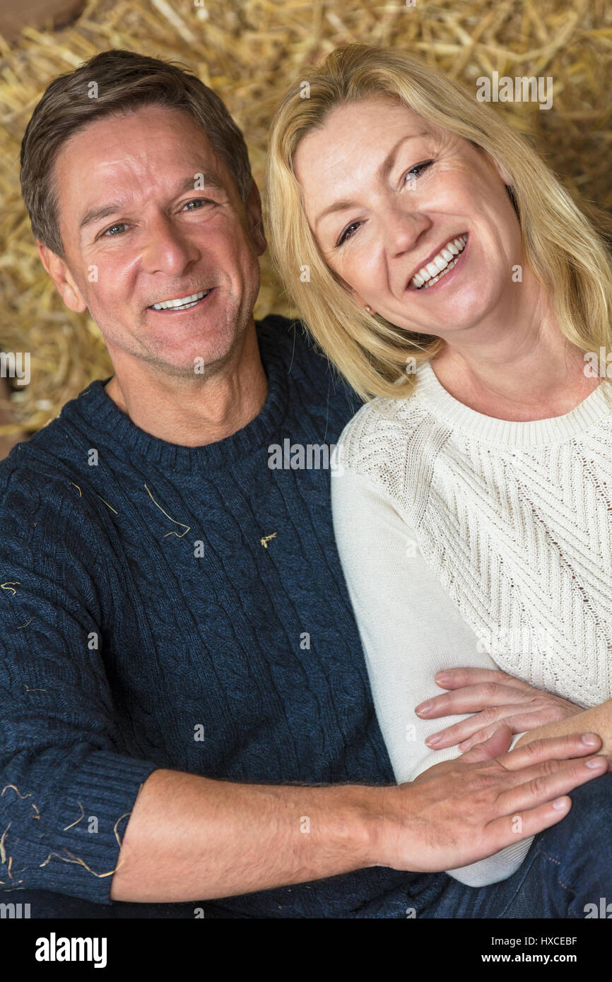 Portrait d'une belle réussite, et happy middle aged man and woman couple sitting rire ensemble sur des bottes de paille ou de foin Banque D'Images