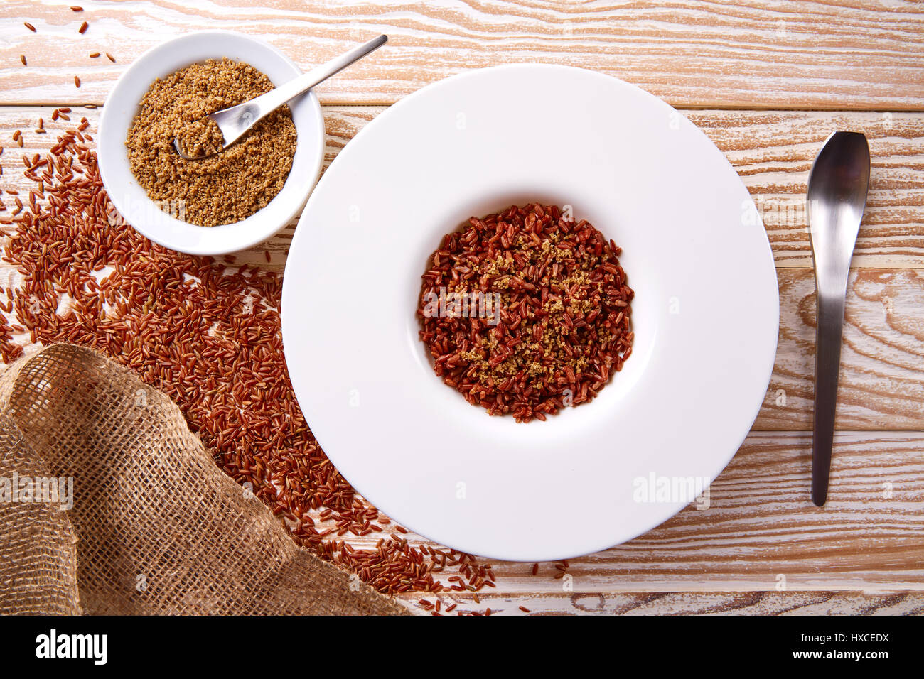 Riz sauvage rouge avec du sésame gomasio assaisonnement dans une assiette blanche sur planche de bois Banque D'Images
