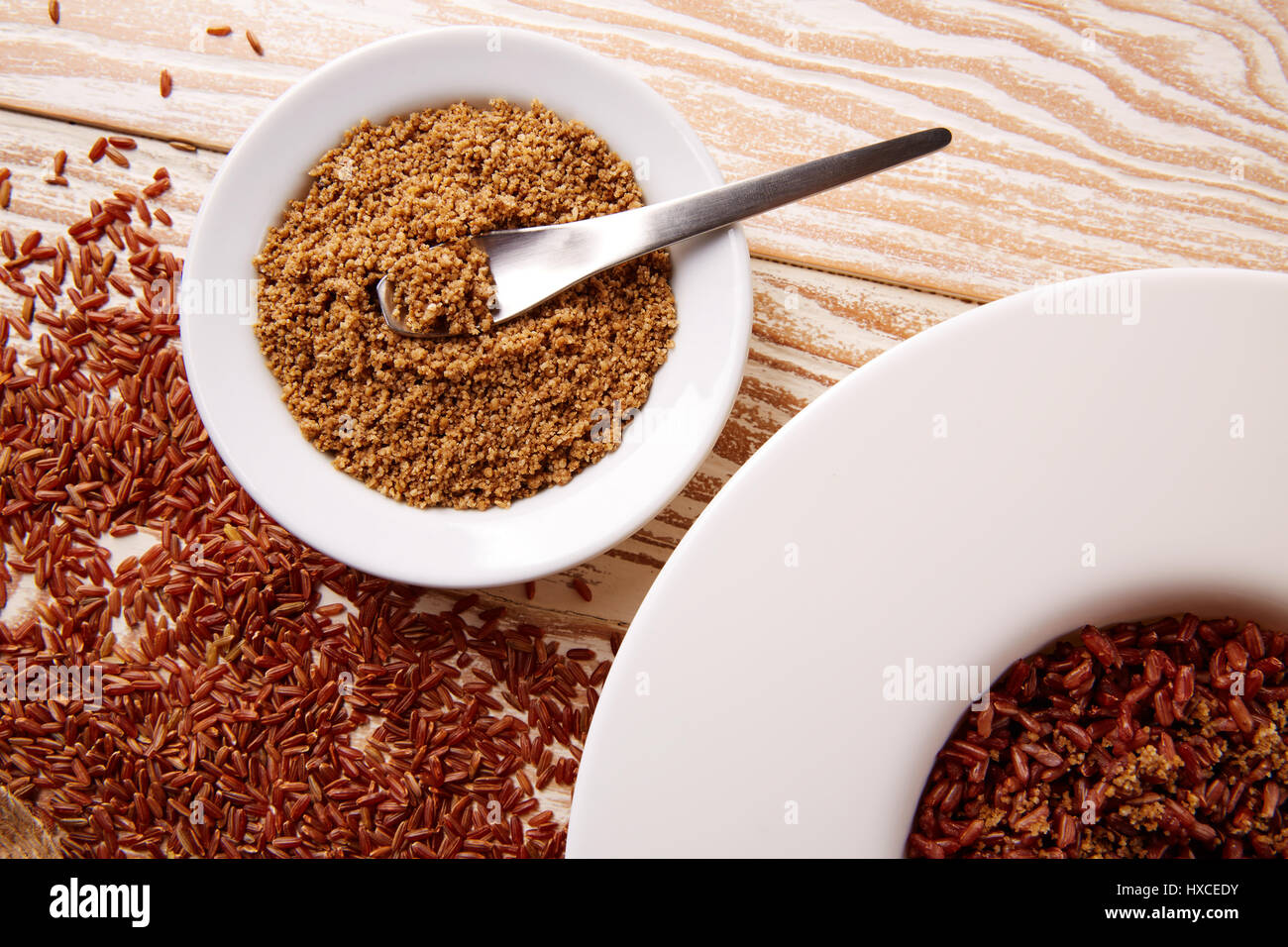 Riz sauvage rouge avec du sésame gomasio assaisonnement dans une assiette blanche sur planche de bois Banque D'Images
