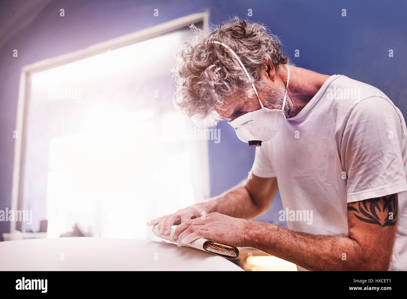 L'accent homme portant un masque de protection de surf dans l'atelier de ponçage Banque D'Images