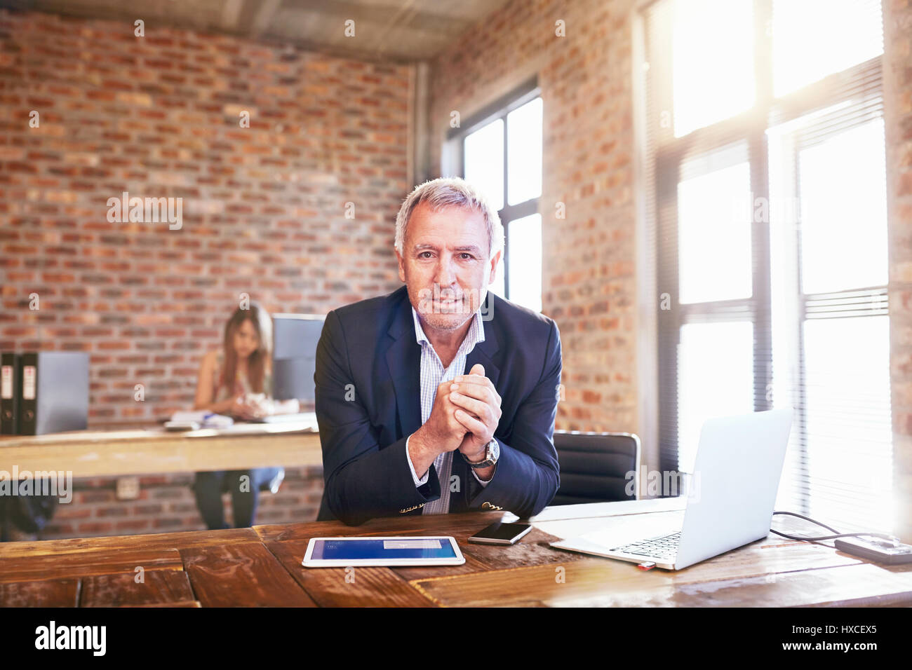 Portrait confident businessman with digital tablet and laptop in office Banque D'Images