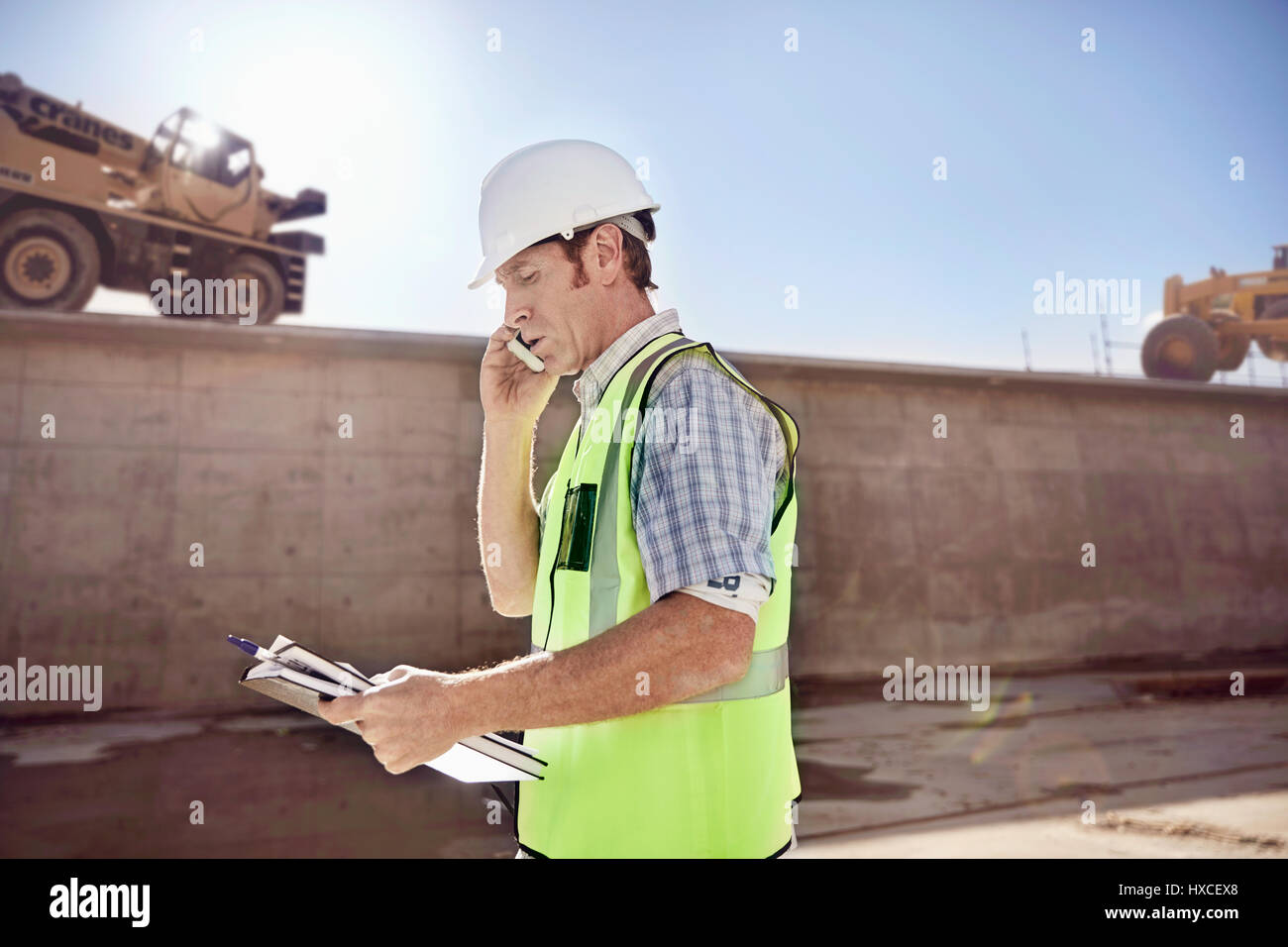Contremaître Construction Worker talking on cell phone at construction site ensoleillé Banque D'Images