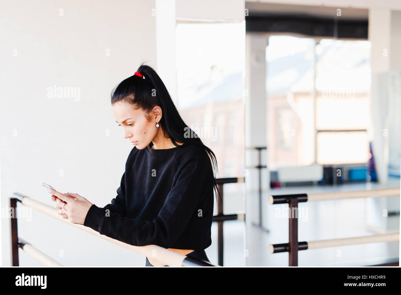 Girl leaning on barres asymétriques à la recherche dans le téléphone Banque D'Images