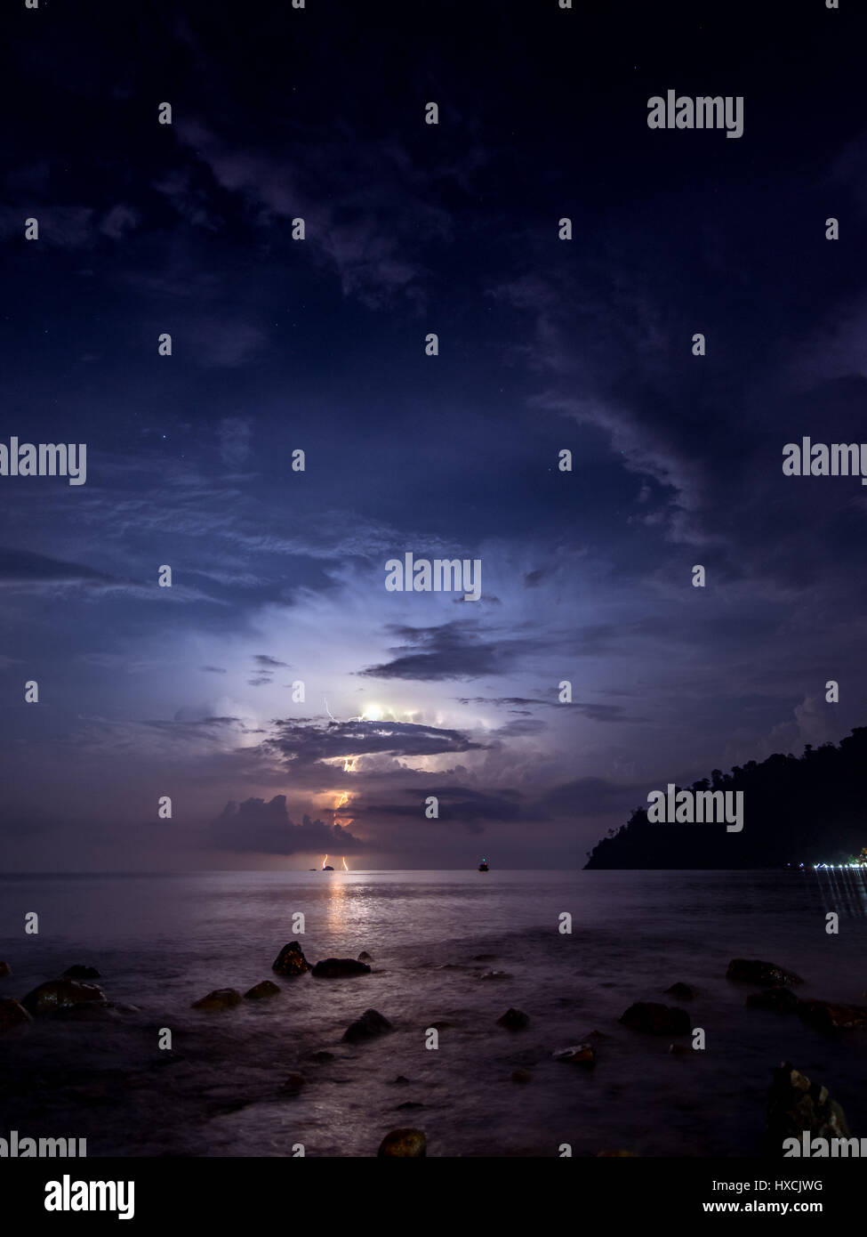 Une tempête de foudre illuminant le ciel nocturne dans la distance du point de vue de l'ABC sur la plage l'île de Tioman, Malaisie. Banque D'Images