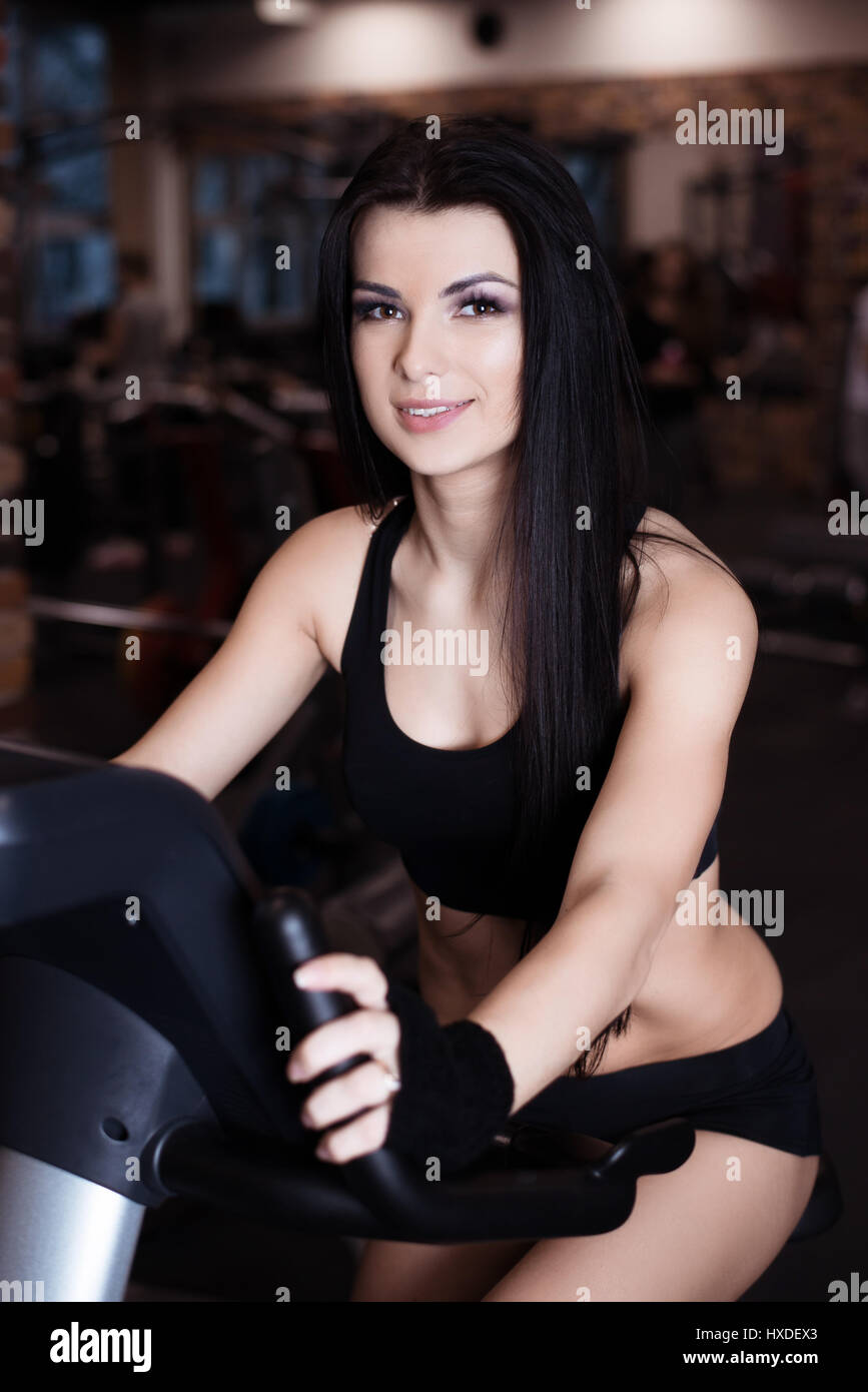 Muscular young woman wearing sportswear formation sur les vélos d'exercice dans la salle de sport. Entraînement cardio intense Banque D'Images