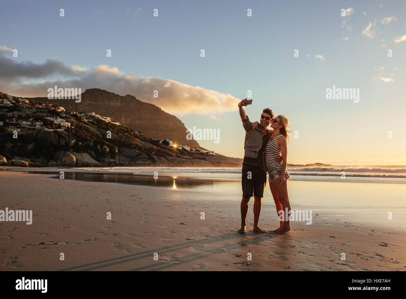 Couple romantique avec selfies téléphone mobile à la plage. Homme et femme sur la mer prendre au coucher du soleil. selfies Banque D'Images